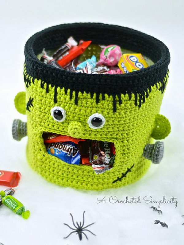 A crocheted frankenstein candy basket with candy in it.