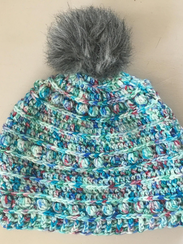 A crocheted hat with a pom pom.
