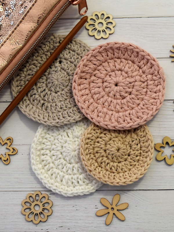 Four crocheted Easter coasters on a wooden table.