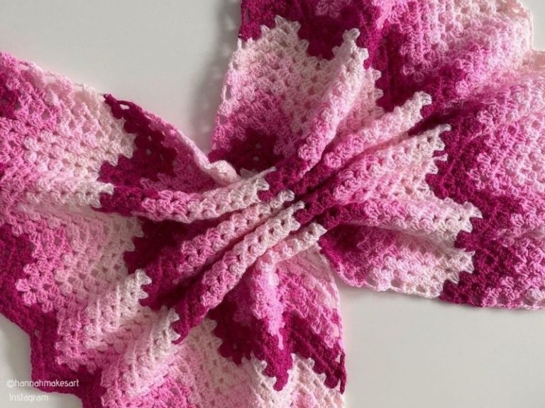 A pink and white crocheted afghan on a white surface, featuring the Granny Ripple Blanket crochet pattern.