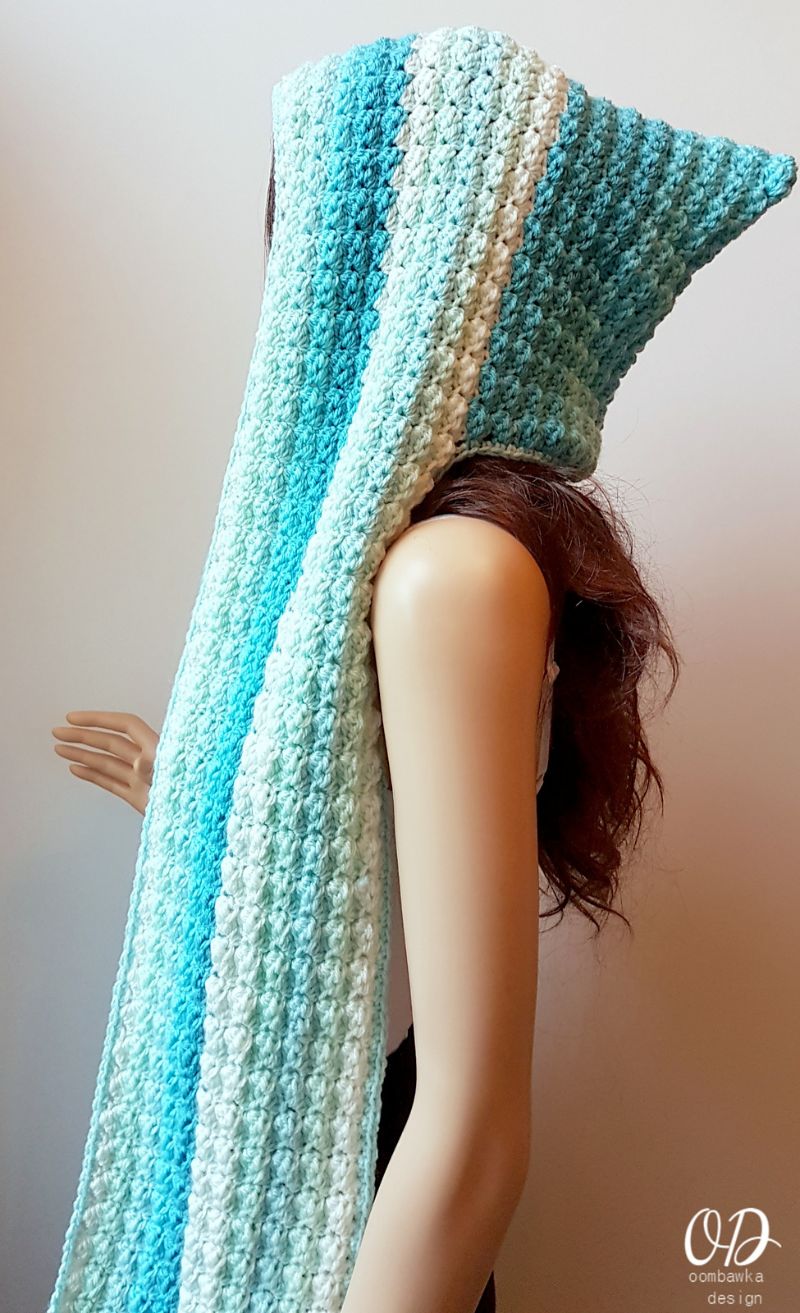 A mannequin wearing a blue and white crocheted scarf.