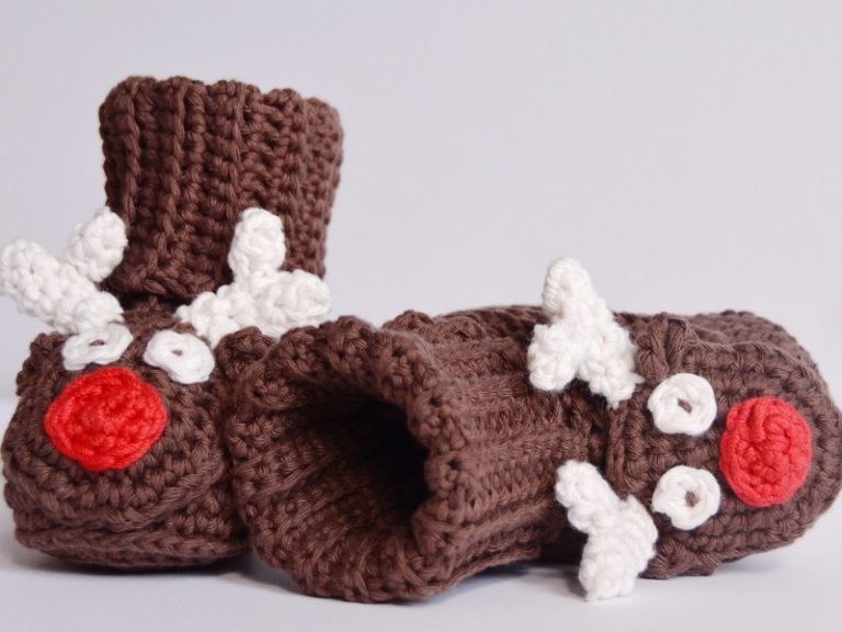 A pair of free crocheted reindeer booties on a white surface.