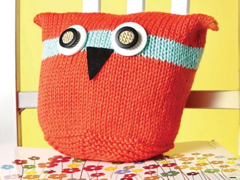 An orange knitted owl sitting on a chair.