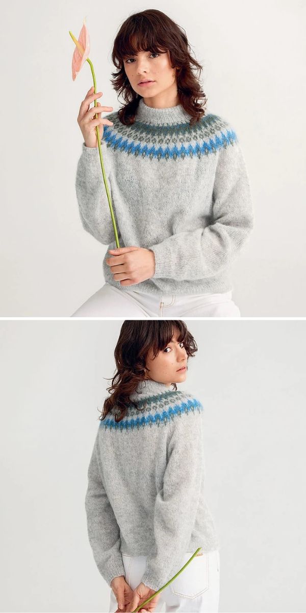 A woman is holding a flower in her hand while wearing a grey sweater.