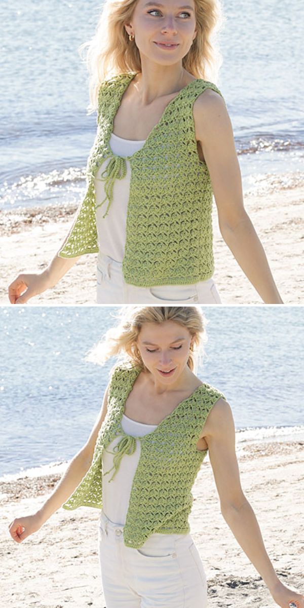 A woman wearing a light green crochet celtic knot vest over a white top and white pants stands and walks on a sandy beach near the water.
