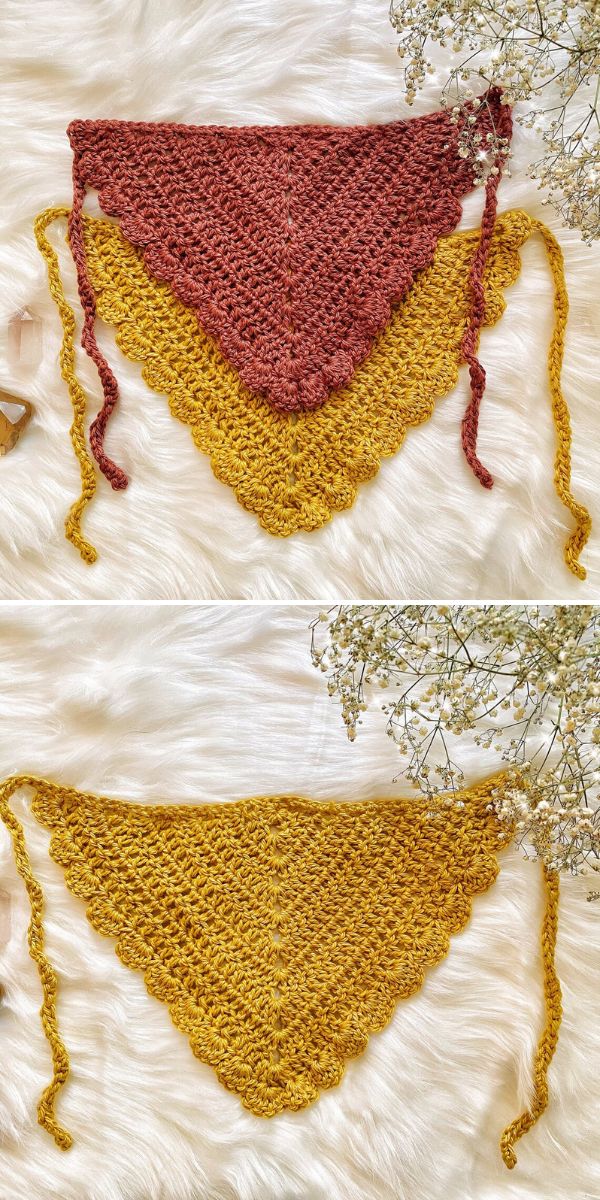 Two triangular crochet shawls, one in solid gold and one layered with gold and rose colors, are displayed on a white fur surface with dried flowers nearby.