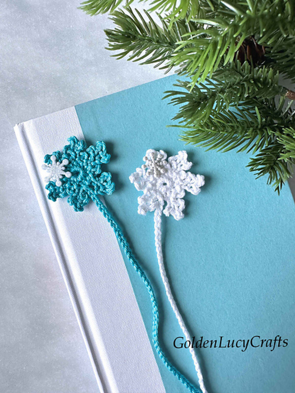 Two crocheted snowflake bookmarks on top of a book.