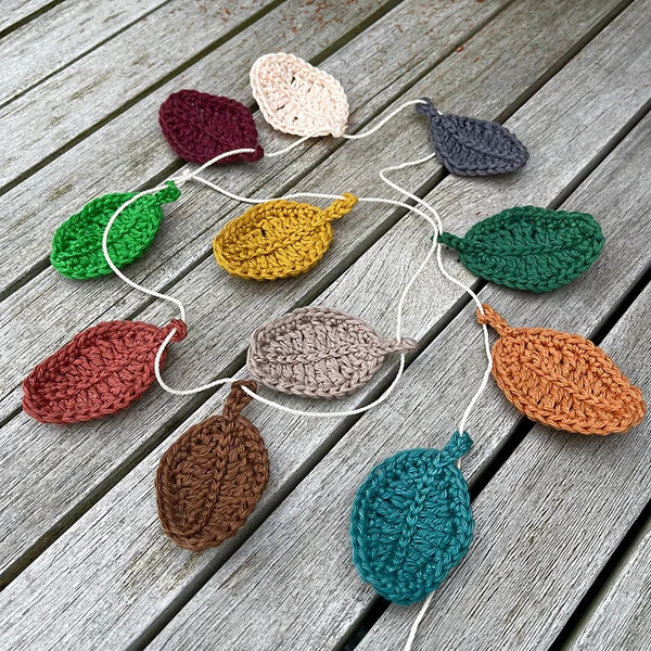 A crocheted leaf garland on a wooden table.