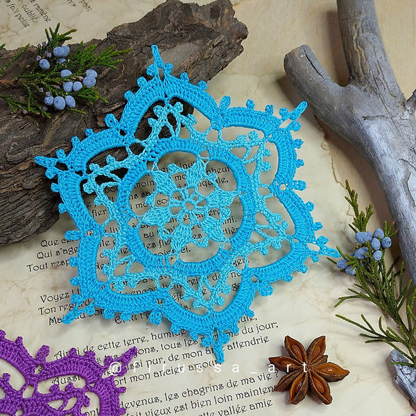 A blue and purple crocheted snowflake on top of a book.