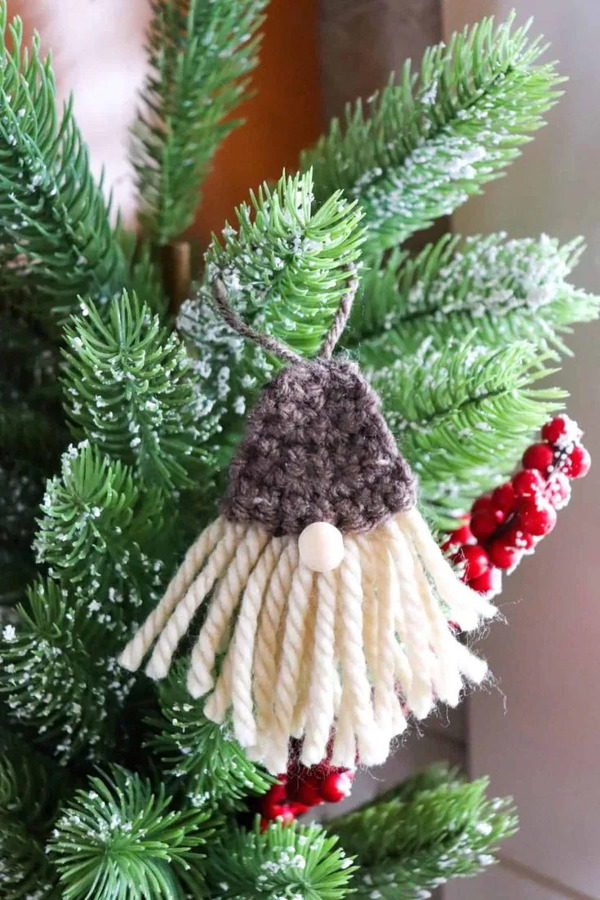 A crocheted santa hat hanging on a christmas tree.
