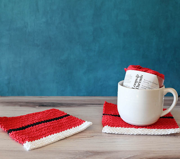 Two knitted coasters on a table next to a cup of coffee.