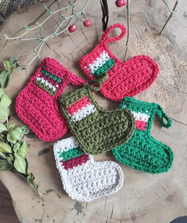 Four crocheted christmas stockings on a wooden table.