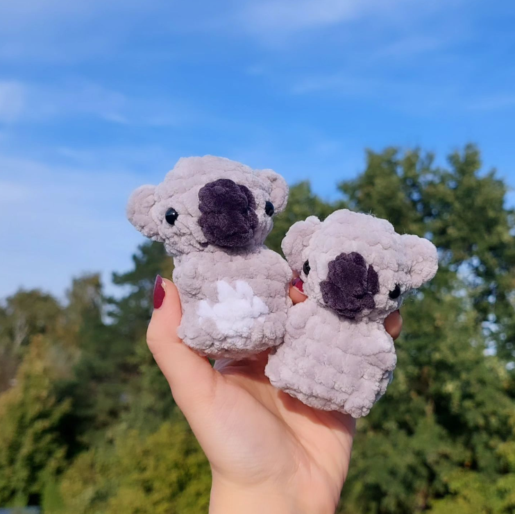 Two koala stuffed animals in a person's hand.