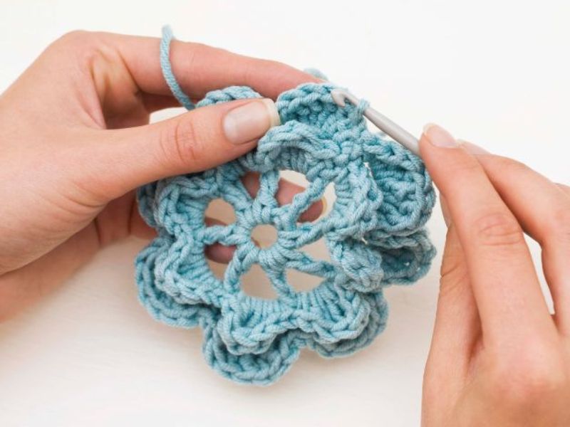 a person holding a crochet hook and crocheting