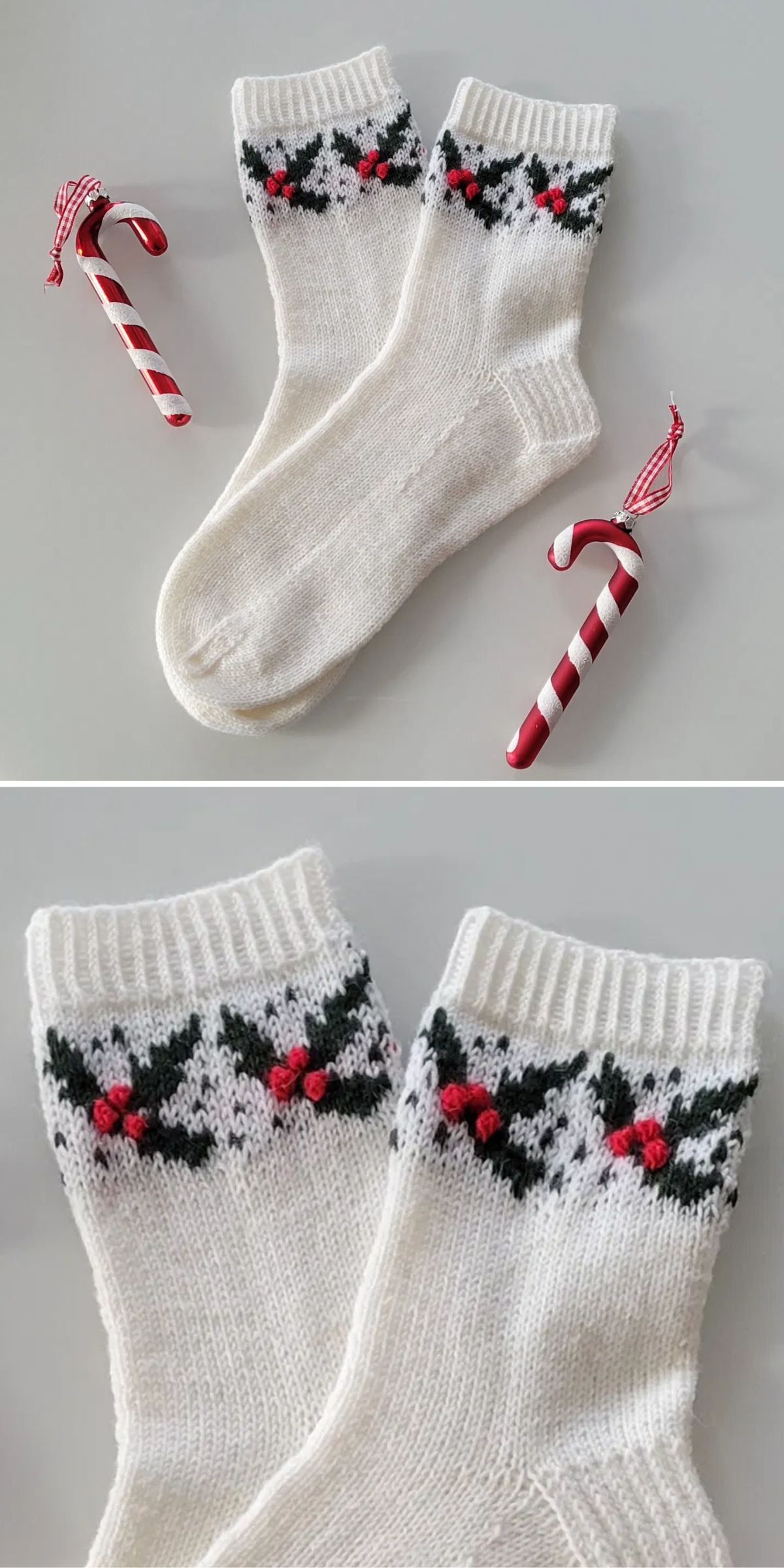 White knitted socks with holly patterns are laid next to two candy canes on a gray surface.