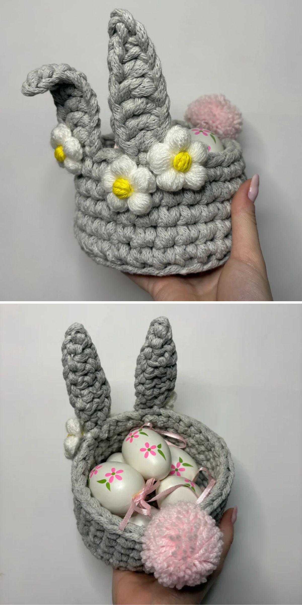 A hand holds a crocheted gray basket with bunny ears, white and yellow flower accents, a pink pompom tail, and painted Easter eggs inside.