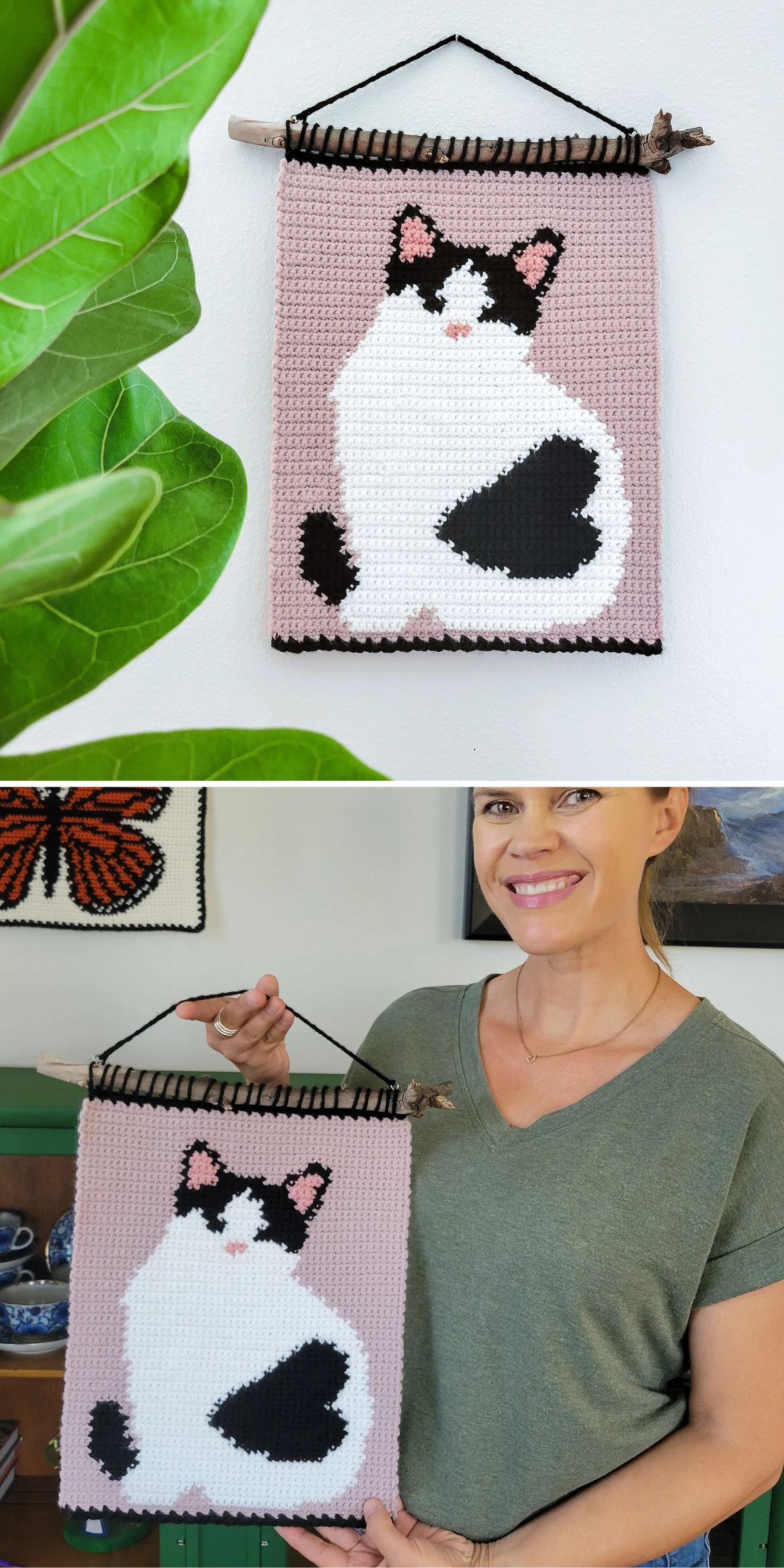 A woman holds a handmade crochet wall hanging featuring a black and white cat on a pink background, mounted on a wooden rod.