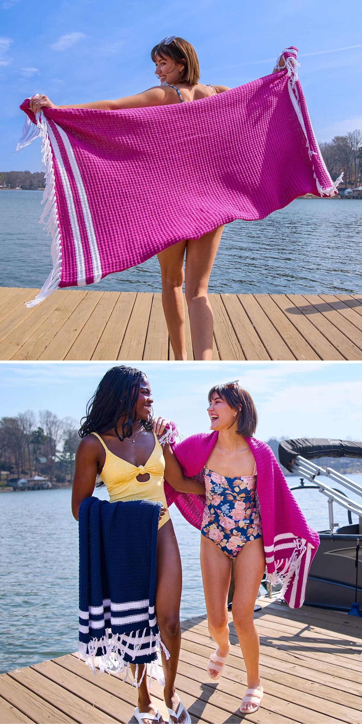 Two women in swimsuits and towels stand and walk on a wooden dock by a lake, with trees and boats in the background under a clear sky.