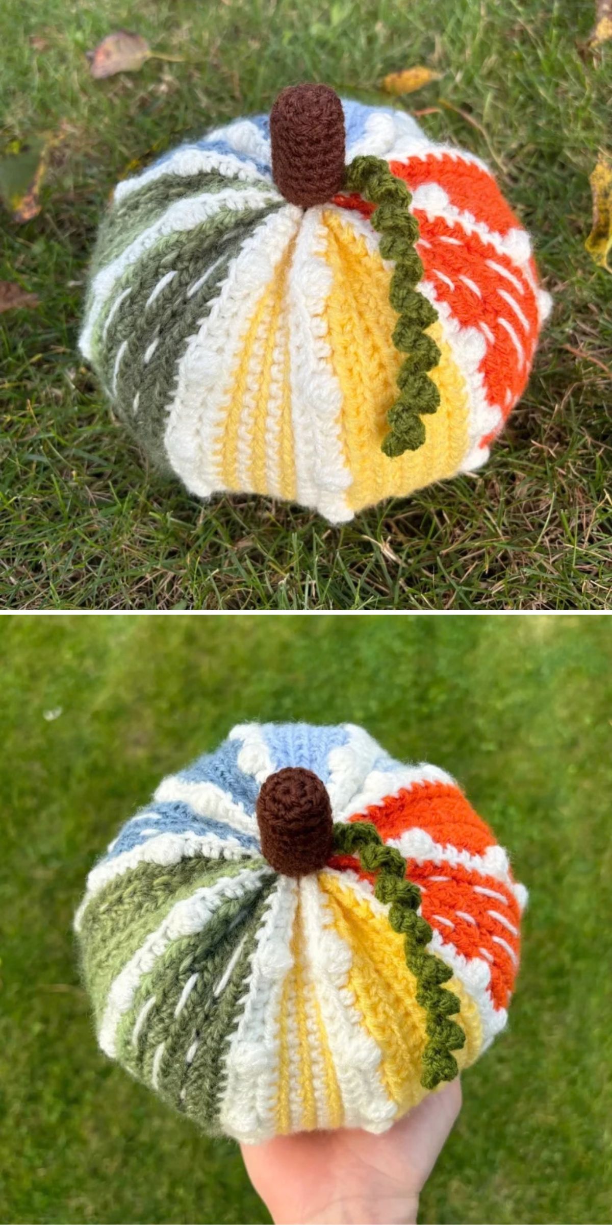 A hand holds a crocheted pumpkin with sections of green, yellow, white, orange, and blue yarn, topped with a brown stem and a curly green leaf, against a grassy background.